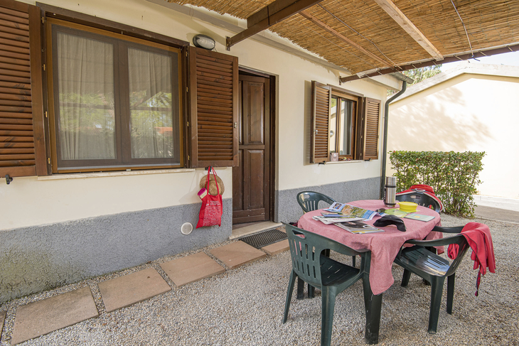 Terrasse eines Bungalows mit Tisch, Stühlen und Wäscheständer.