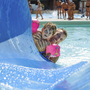 Mann und Kind mit Schwimmflügeln auf Wasserrutsche im Pool.