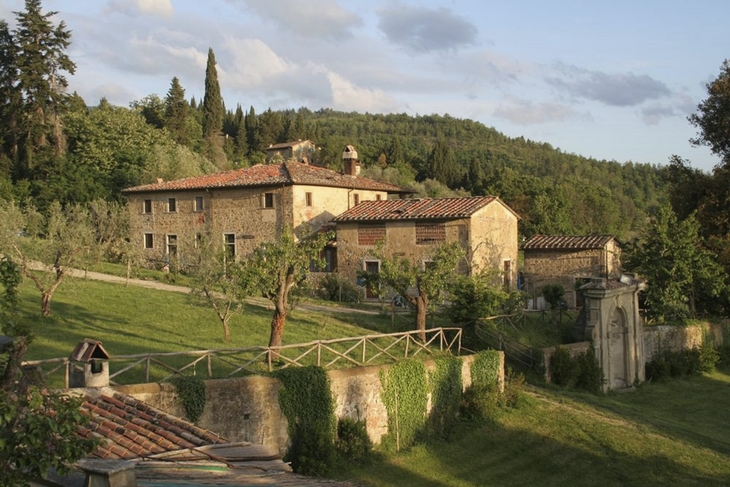 Historische Villa in ländlicher Umgebung mit Bäumen und Hügeln.