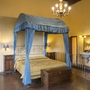 Schlafzimmer mit Himmelbett, Holzboden, Kronleuchter und Waschbecken.