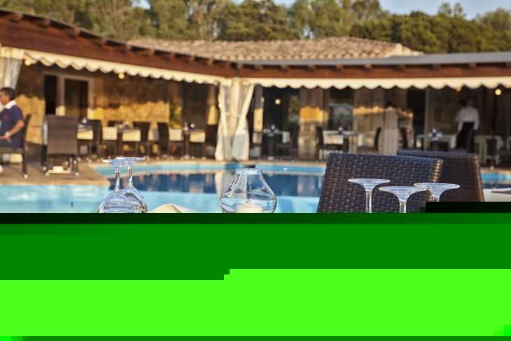 Gedeckter Tisch im Außenbereich eines Restaurants mit Pool im Hintergrund.