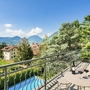 Terrasse mit Blick auf Pool, Garten und Berge bei klarem Himmel.