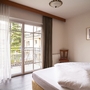 Doppelzimmer mit Balkon und großen Fenstern, geschmackvoll eingerichtet.
