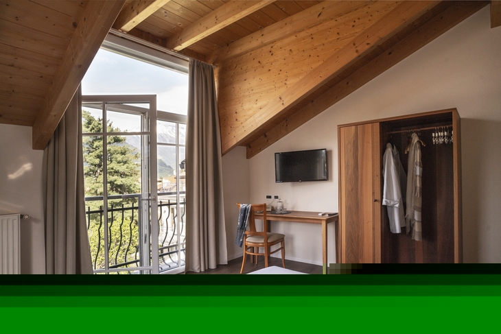 Doppelzimmer mit Holzbalkendecke, Balkon mit Bergblick, Schreibtisch und Schrank.