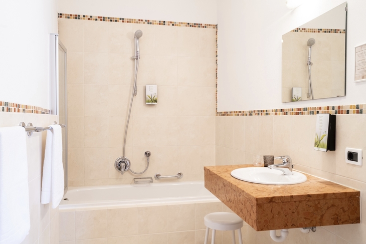 Modernes Badezimmer mit Badewanne, Waschbecken und Spiegel in heller Farbgebung.