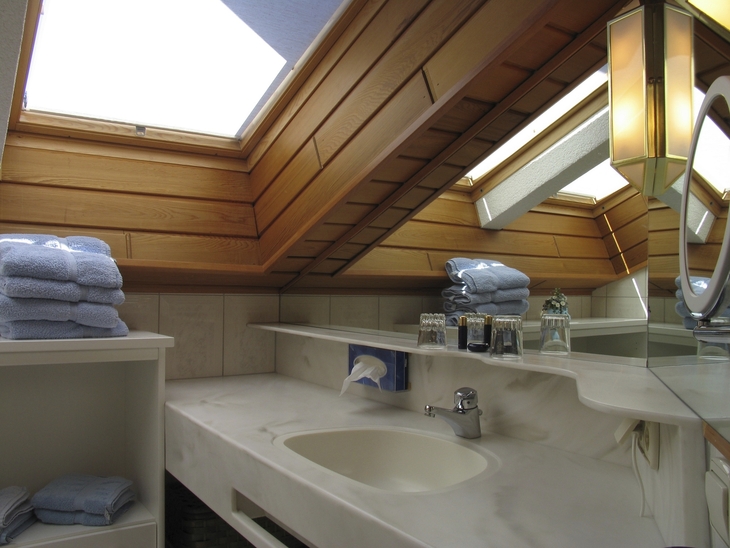 Waschbecken im Dachgeschoss-Badezimmer mit Handtüchern und Dachfenstern.