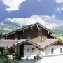 Ein Landhaus vor Alpenkulisse bei klarem Himmel.