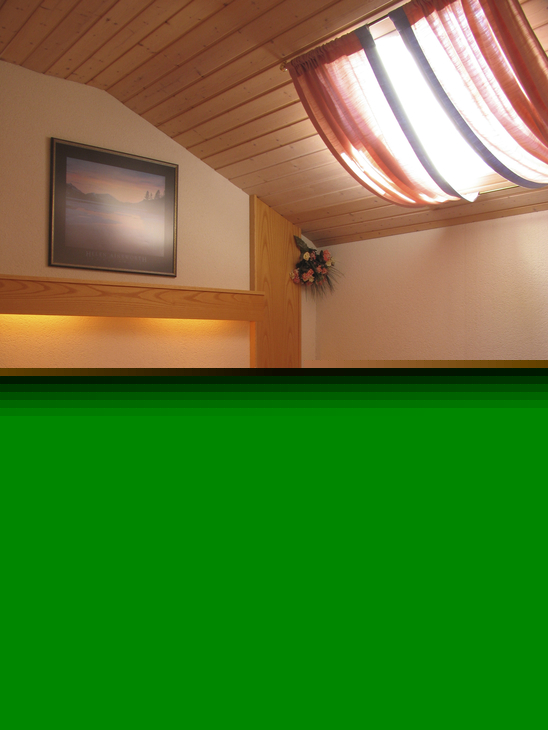 Doppelbett in gemütlichem Holz-Schlafzimmer mit Rotlichtbeleuchtung und Dachfenster.