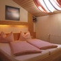Doppelbett in gemütlichem Holz-Schlafzimmer mit Rotlichtbeleuchtung und Dachfenster.