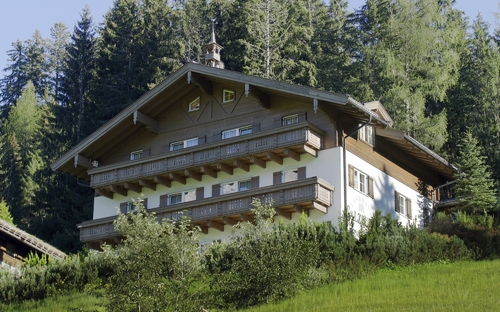 Ein Landhaus in Salzburg umgeben von Bäumen und Wiese.