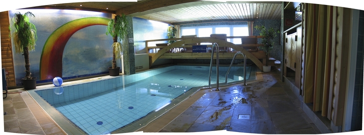 Innenpool mit Wandbild eines Regenbogens und Pflanzen im Landhaus Salzburg.