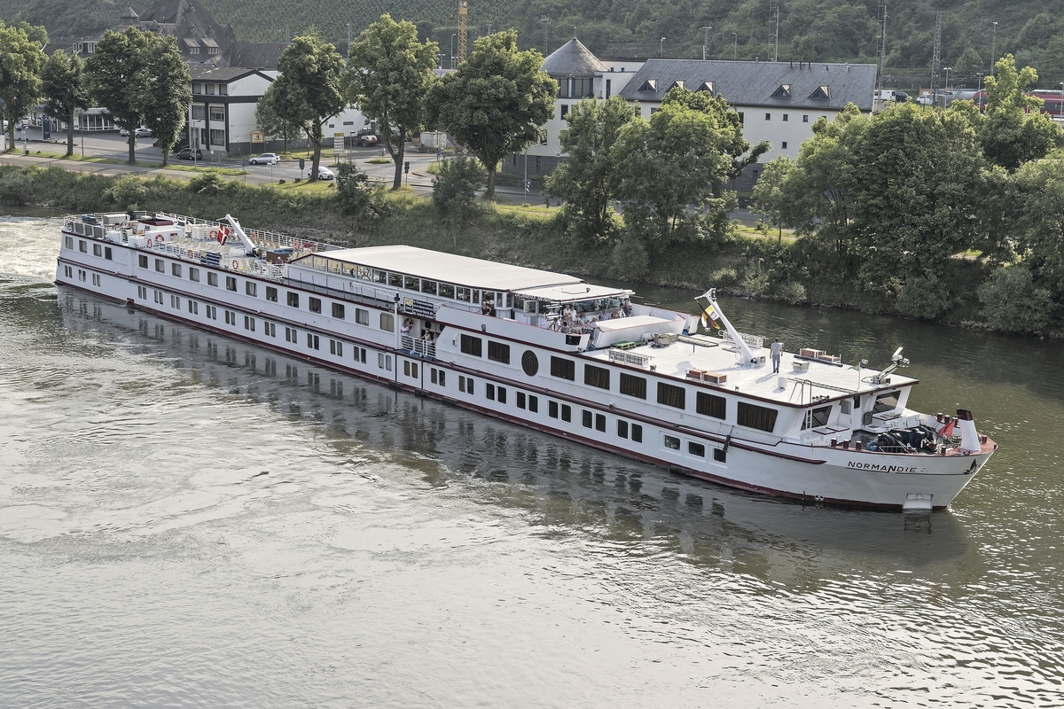 Flusskreuzfahrtschiff MS Normandie auf einem Fluss vor grüner Uferlandschaft.