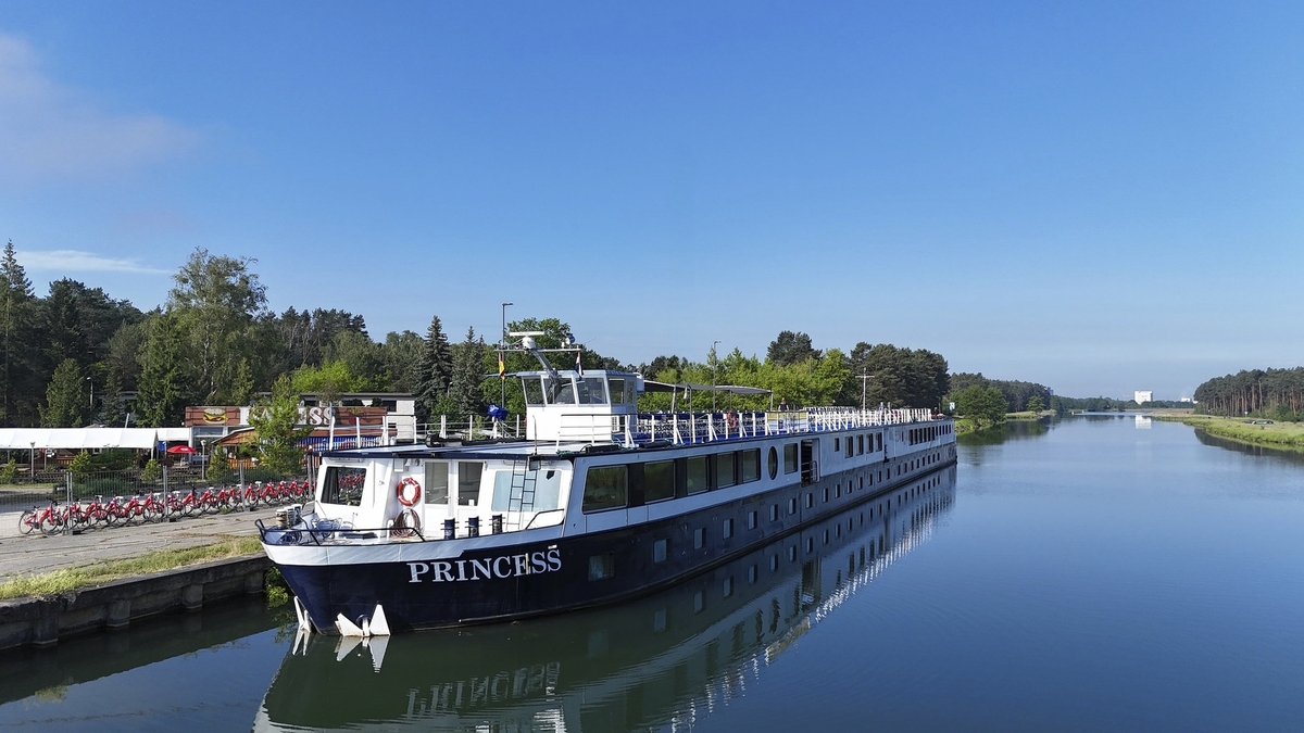 Flusskreuzfahrtschiff MS Princess auf einem ruhigen Wasserweg bei klarem Himmel.
