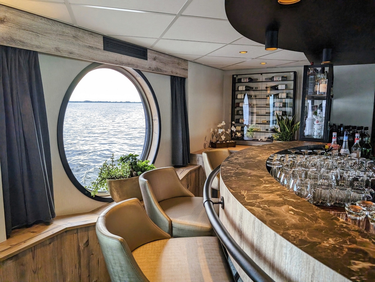 Schiffbar mit rundem Fenster, Blick aufs Wasser, elegante Einrichtung.