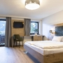 Modernes Schlafzimmer mit Doppelbett, Schreibtisch und Blick aus dem Fenster.