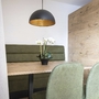 Essbereich mit Holztisch, grüner Sitzbank und modernen Stühlen in einem Studio