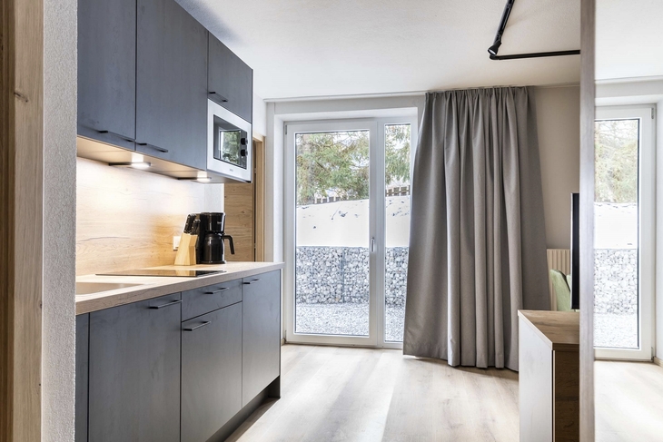 Moderne Küchenzeile mit Mikrowelle und Kaffeemaschine in hellem Raum mit Fenstertür.