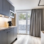 Moderne Küchenzeile mit Mikrowelle und Kaffeemaschine in hellem Raum mit Fenstertür.