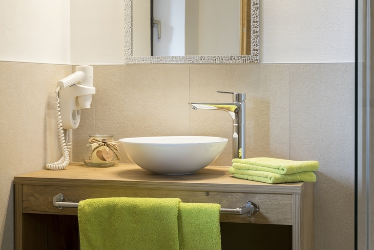 Waschbecken und Toilettenartikel in einem Badezimmer mit grünen Handtüchern.