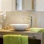 Waschbecken und Toilettenartikel in einem Badezimmer mit grünen Handtüchern.
