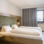 Doppelzimmer mit Holzinterieur und großem Fenster, Gardinen und Doppelbett.