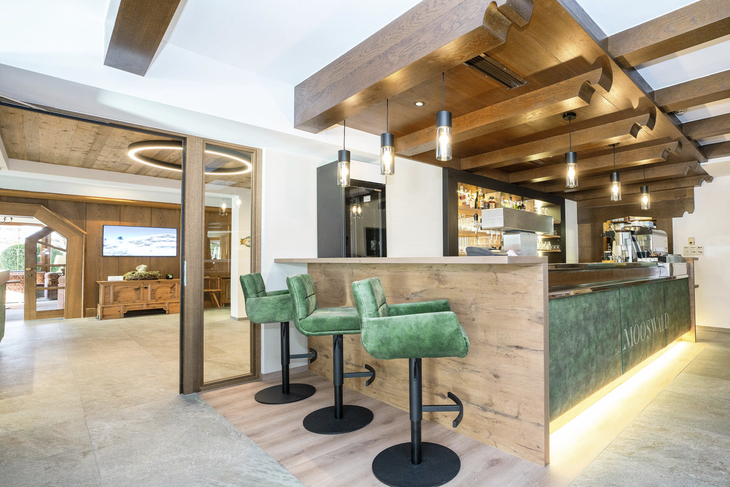 Innenansicht eines modernen Restaurants mit Holzelementen und Barhockern.