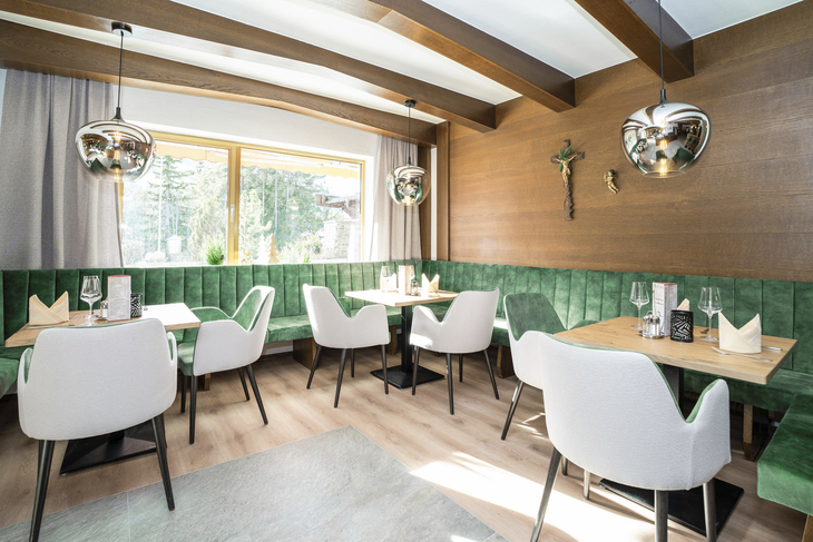 Restaurant-Innenraum mit grüner Sitzbank, Holzwänden und modernen Hängelampen.