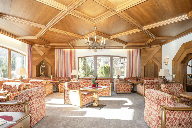 Heller Speisesaal mit roten Polstermöbeln und holzverkleideter Decke.