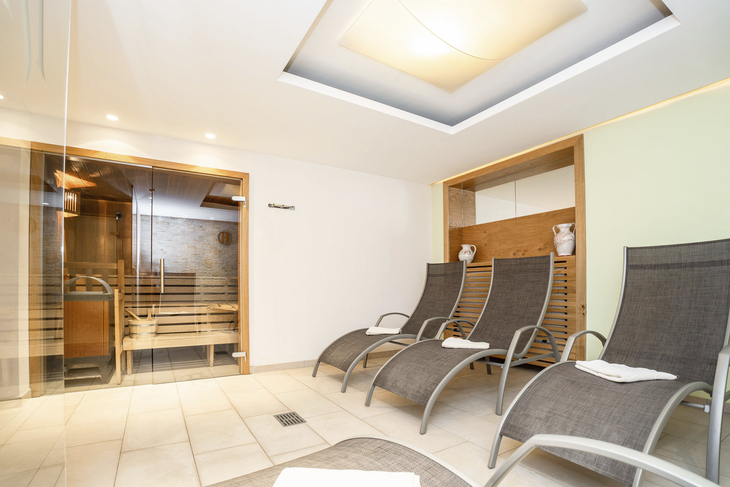 Innenansicht einer modernen Sauna mit Liegestühlen und Holzvertäfelung.