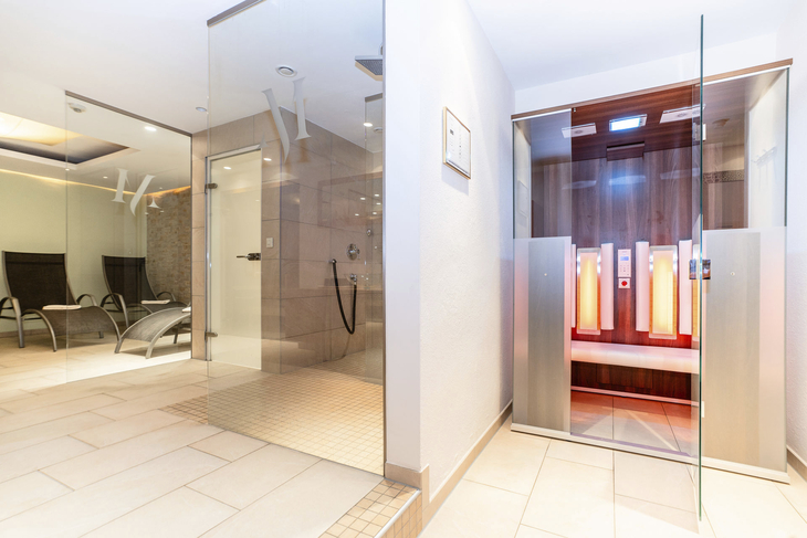 Innenbereich einer modernen Sauna mit Glastüren und Liegestühlen