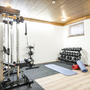 Fitnessraum mit Geräten, Hanteln und Yogamatten in einem hell erleuchteten Raum.