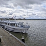 Flusskreuzfahrtschiff MS Rigoletto am Ufer unter bewölktem Himmel.
