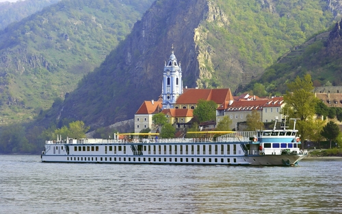 Flusskreuzfahrtschiff MS Prinzessin Katharina auf einem Fluss vor einer Berglandschaft.
