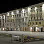 Historische Gebäude in Linz bei Nacht, beleuchtet mit Blumenbeeten im Vordergrund.