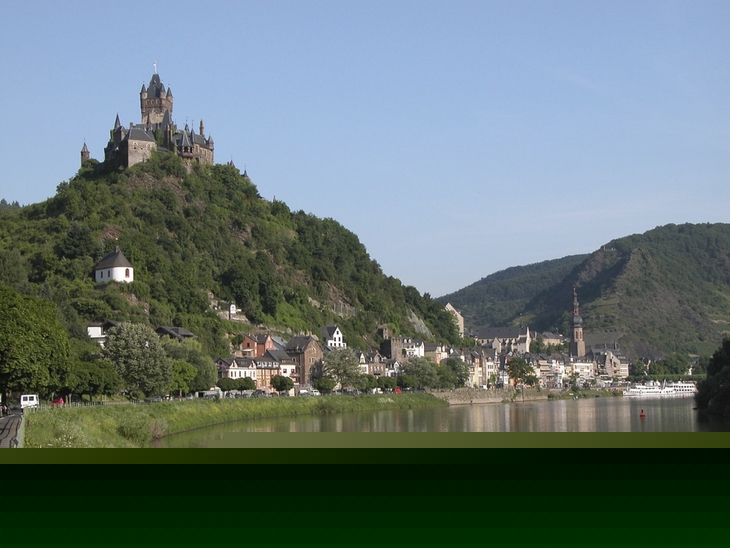Burg Cochem auf Hügel, umgeben von Stadt und Flusslandschaft.