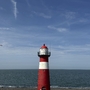 Roter Leuchtturm in Westkapelle vor blauem Himmel und Meer.