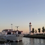 Ein Schiff im Hafen von c bei Sonnenuntergang neben einem Leuchtturm.