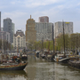Hafenkanal mit historischen Schiffen und moderner Skyline in Rotterdam.