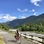 Radfahrer auf dem Alpe-Adria-Radweg in bergiger Landschaft bei sonnigem Wetter.
