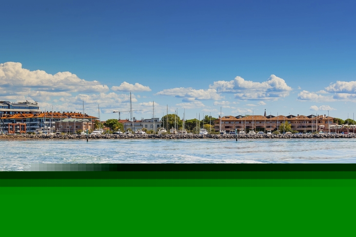 Küste von Grado mit Booten und blauen Himmel im Hintergrund.