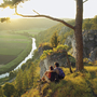 Zwei Wanderer genießen den Ausblick über das Altmühltal bei Sonnenuntergang.