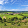 Panoramablick über grüne Landschaft und Dorf im Altmühltal an einem sonnigen Tag.
