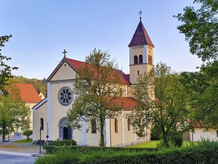 Kirche in grüner Landschaft im Altmühltal bei klarem Himmel.