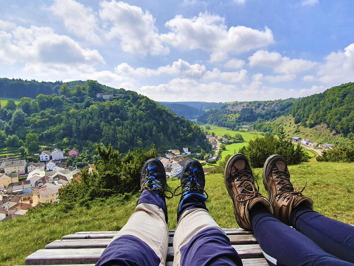 Zwei Personen mit Wanderschuhen sitzen auf einer Bank mit Blick auf das Altmühltal.