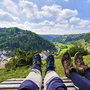 Zwei Personen mit Wanderschuhen sitzen auf einer Bank mit Blick auf das Altmühltal.