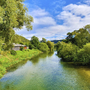 Blick auf Fluss und grüne Landschaft im Altmühltal unter blauem Himmel mit Wolken.