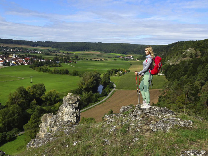 Wanderer mit rotem Rucksack blickt von Aussichtspunkt auf das Altmühltal.