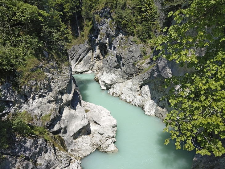 Klarer Fluss zwischen Felsen und Bäumen in einer Schlucht bei sonnigem Wetter.