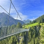 Hängebrücke in Holzgau, umgeben von alpiner Landschaft und grünen Wäldern.