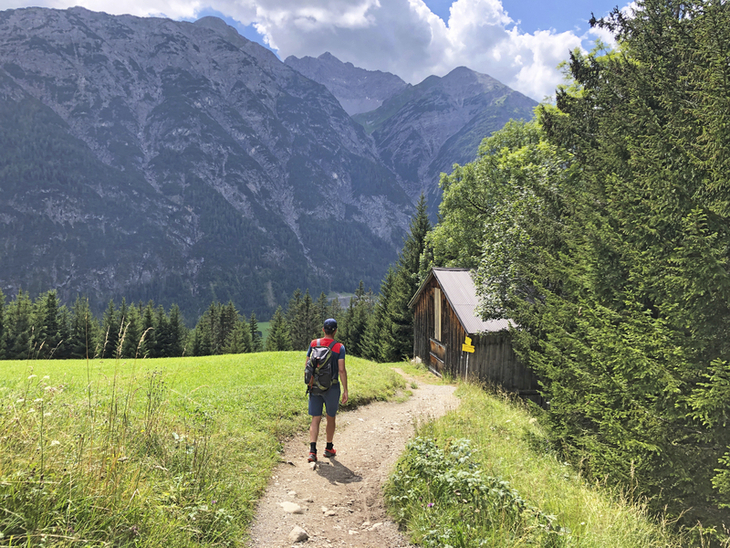 Wanderer auf Bergweg vor beeindruckender Alpenkulisse am Lechweg.